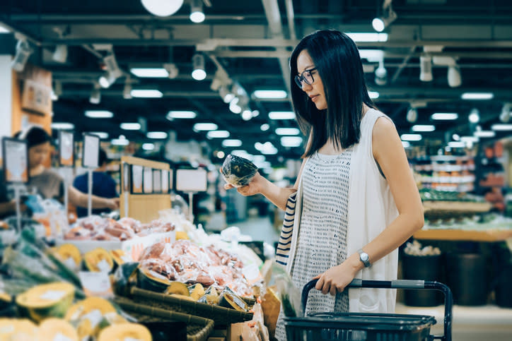 image of a woman in grocery store inspecting a piece of produce