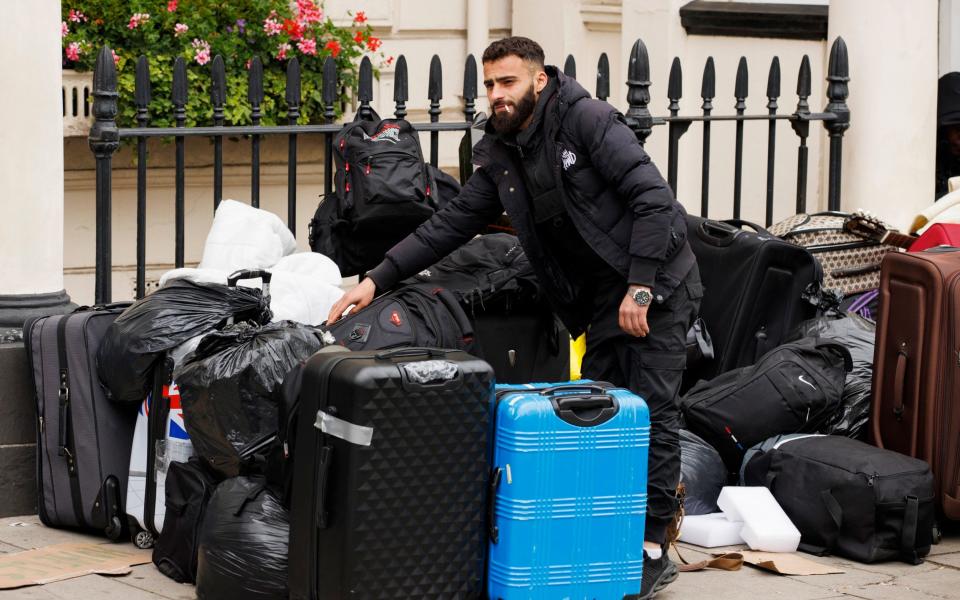 Man beside large pile of suitcases on the street - Jamie Lorriman for The Telegraph