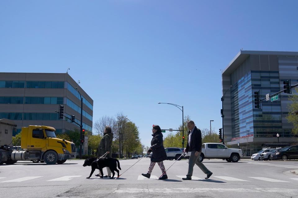 Maureen Reid, left, and her guide dog, Gaston, cross a street in Chicago with Sandy Murillo, center, and Geovanni Bahena, relying on an audible signal for the blind, on April 26, 2023. Faced with a growing backlash, the U.S. Census Bureau announced on Feb. 6, 2024, that it is pausing plans to change how it asks people about disability in its most comprehensive survey, a move that would have overhauled how disabilities are defined by the nation's largest statistical agency.