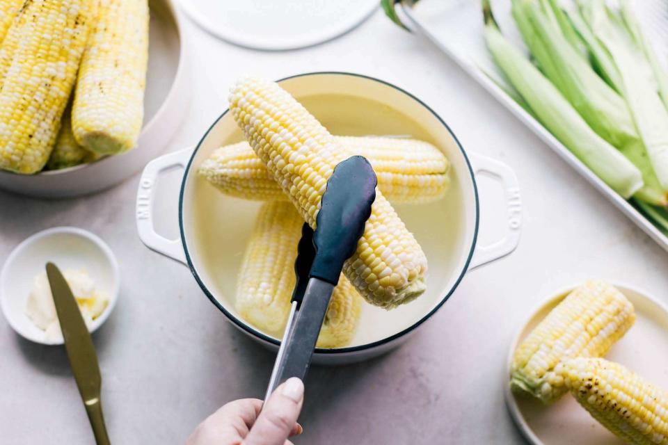 holding corn on the cob with tongs