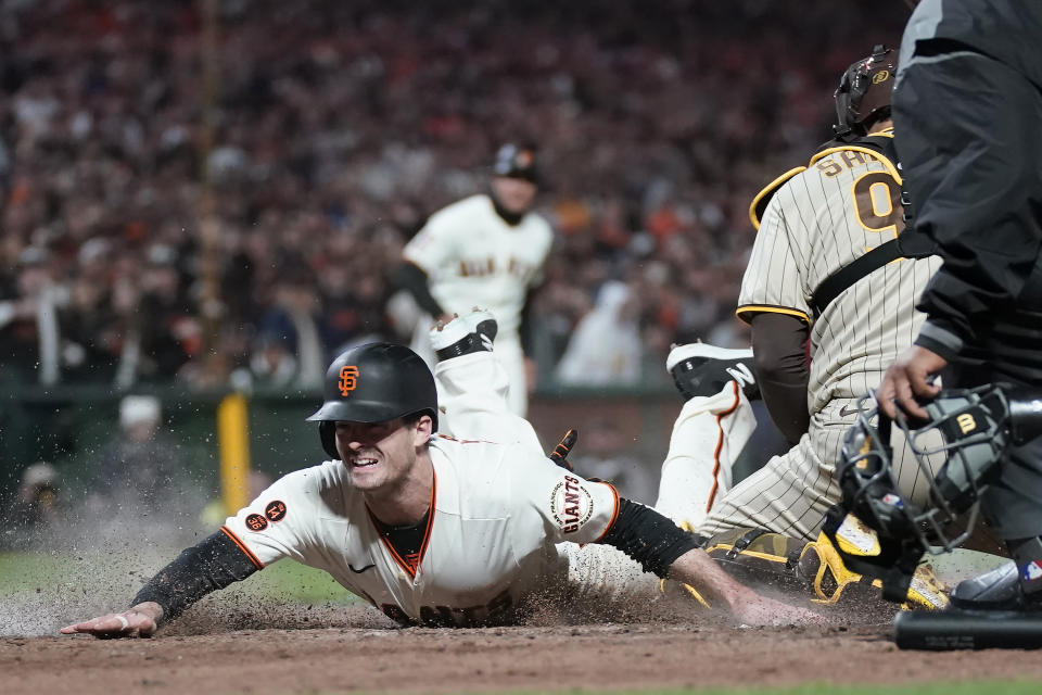 San Francisco Giants' Mike Yastrzemski, left, slides home to score past San Diego Padres catcher Gary Sanchez during the ninth inning of a baseball game in San Francisco, Monday, June 19, 2023. (AP Photo/Jeff Chiu)