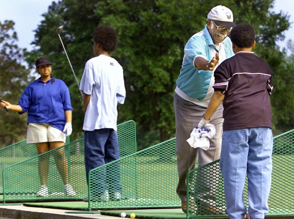 In this 2006 photo, Robert Mungen congratulates Martez Gordon as Nick Thompson and Brittany Moore practice swings during a golf class that Mungen teaches at Jake Gaither Golf Course.