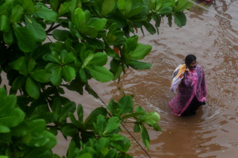 A resident wades along a waterlogged road after heavy rains following Cyclone Nivar landfall in Puducherry on November 26, 2020. (Photo by ARUN SANKAR/AFP via Getty Images)