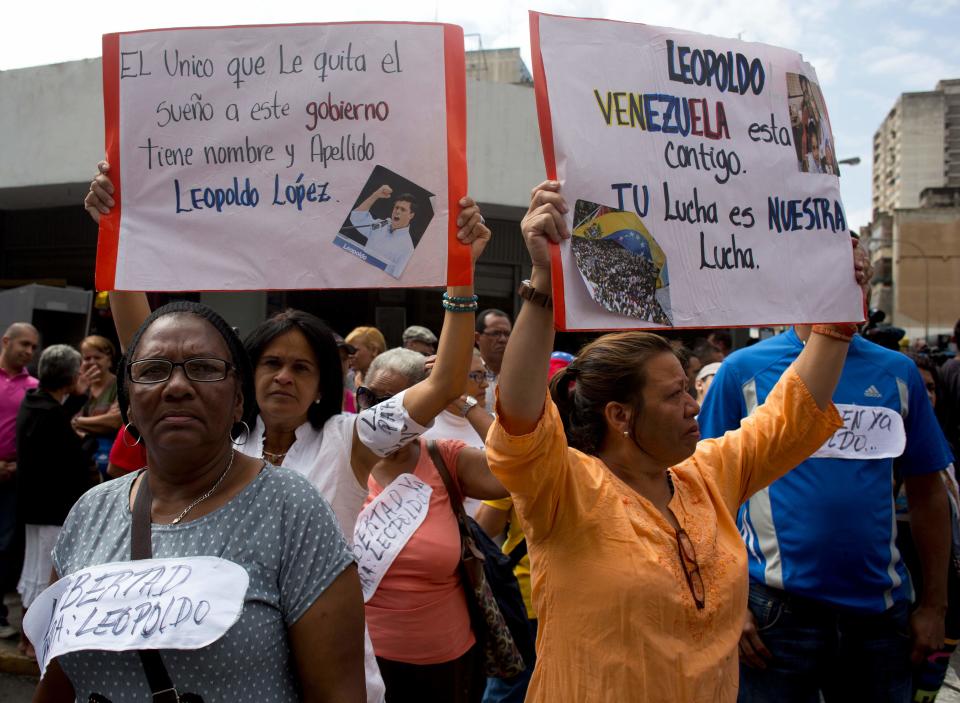 Supporters of opposition leader Leopoldo Lopez hold up posters that read in Spanish " Leopoldo Venezuela is with you, your fight is our fight" and "The only one that robs this government of sleep has a name, Leopoldo Lopez " outside the Palace of Justice in Caracas, Venezuela, Wednesday, Feb. 19, 2014. Following a dramatic surrender and a night in jail, Venezuelan opposition leader Leopoldo Lopez was due in court Wednesday to learn what charges he may face for allegedly provoking violence during protests against the socialist government in the divided nation. (AP Photo/Rodrigo Abd)