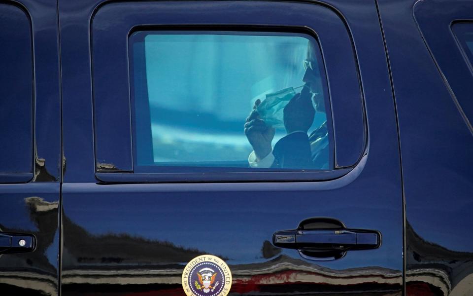 Biden removes his mask inside his fortified car