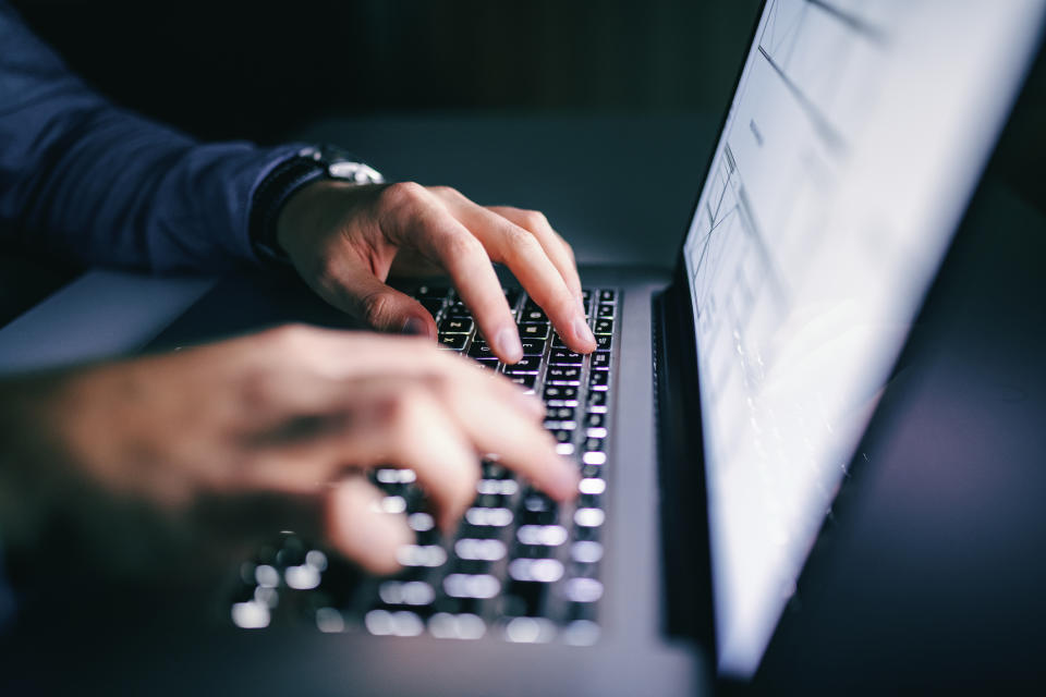 A man's hands typing on a laptop.