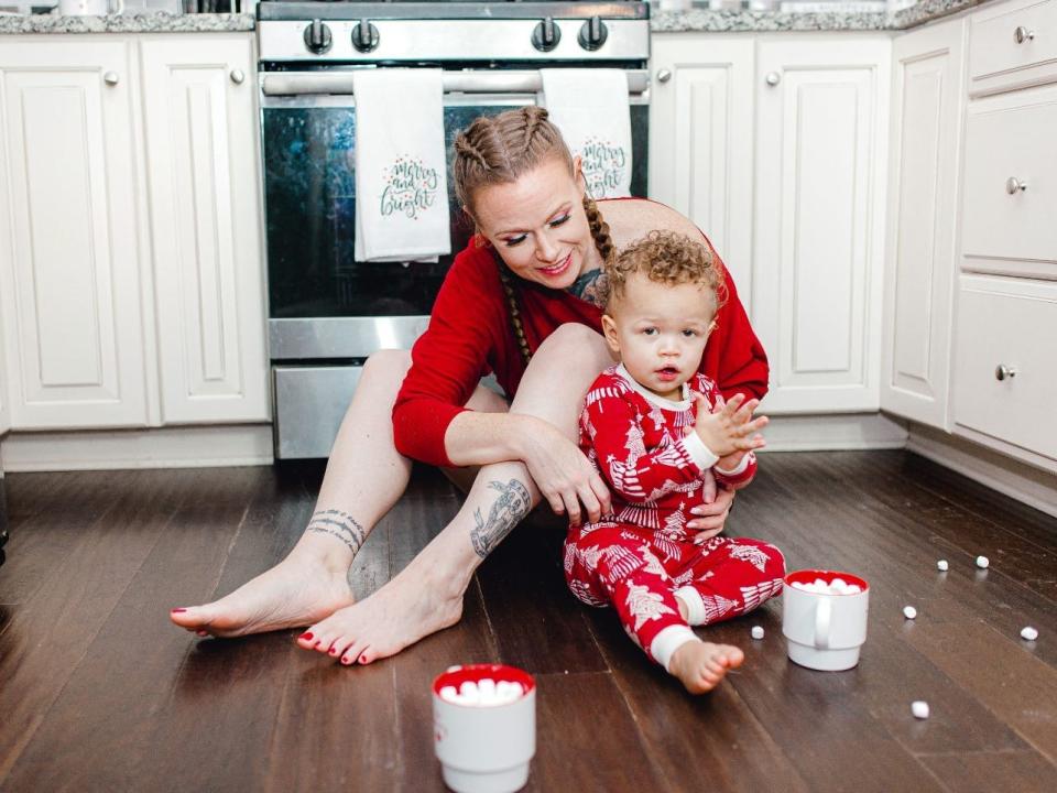 A woman on the floor of a kitchen with her son