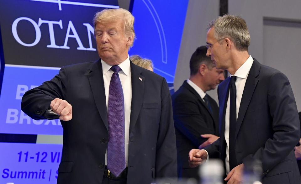 FILE - U.S. President Donald Trump checks his watch as NATO Secretary General Jens Stoltenberg stands beside him, at the Art and History Museum at the Park Cinquantenaire in Brussels, July 11, 2018. NATO is set to celebrate on Thursday, April 4, 2024, 75 years of collective defense across Europe and North America as Russia's war on Ukraine enters its third year. (AP Photo/Geert Vanden Wijngaert, File)