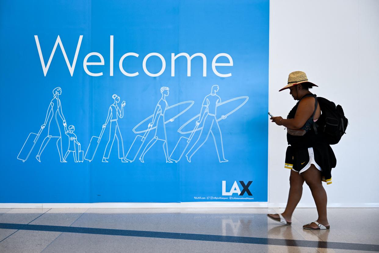 A traveler walks past a welcome sign at Los Angeles International Airport (LAX) in Los Angeles, on August 10, 2022. (Photo by Patrick T. FALLON / AFP)
