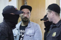 Russian theatre director Kirill Serebrennikov, who was detained and accused of embezzling state funds, is escorted inside a court building upon his arrival for a hearing on his detention in Moscow, Russia August 23, 2017. REUTERS/Tatyana Makeyeva