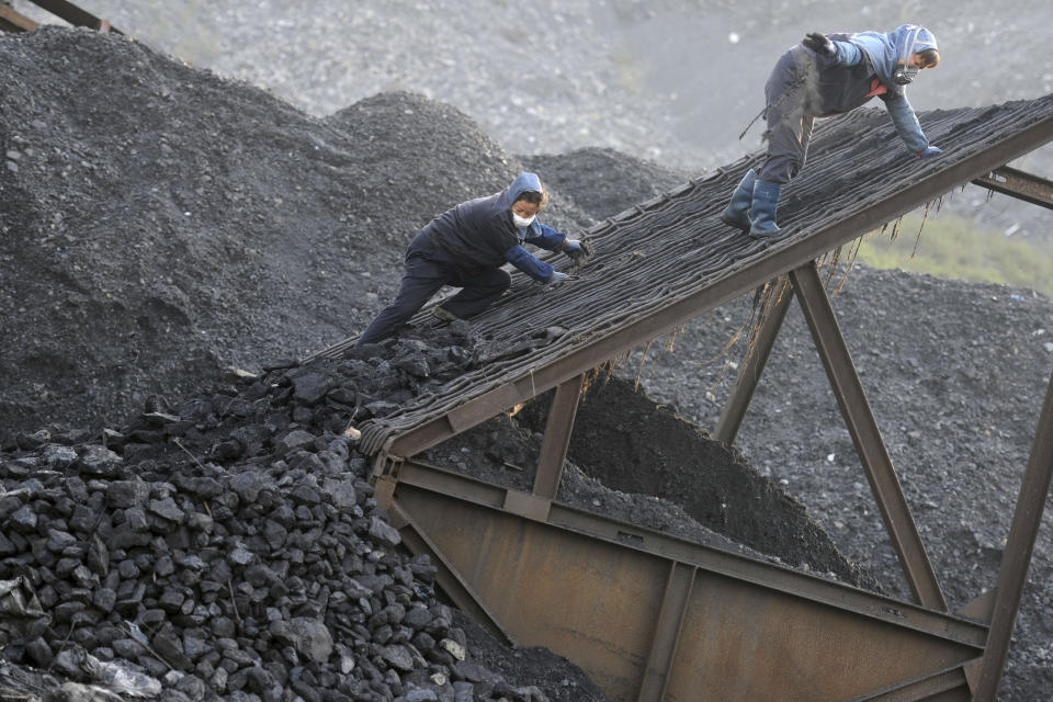 Workers sort coal at the yard of a coal mine in Huaibei in central China's Anhui province on Nov. 3, 2016. China, the world's biggest coal user, said Tuesday, April 27, 2021 that the fossil fuel will play a less dominant role in its energy mix and that, despite plans to build new coal-fired power plants, the country won't use it on a wide scale. (Chinatopix via AP)