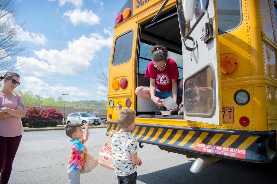 Theo, 4, left, and Henry Eliason, 5, deliver a tin of homemade Easter cookies to bus driver Melissa Mobley as she delivers meals to students from Buncombe County Schools at the Hawthorne at Southside apartment complex on April 9, 2020.