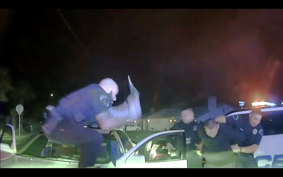 In a still image captured from video, then-Officer Jeffrey Aguirre jumps over the hood of Jose Lenor Garcia's car while he was being arrested on Nov. 21, 2020. Aguirre struck Garcia with a baton about five times.