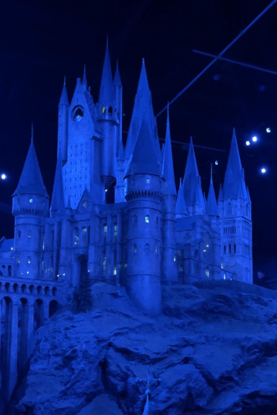 Model of Hogwarts Castle in a dimly lit setting with spotlights and a starry backdrop