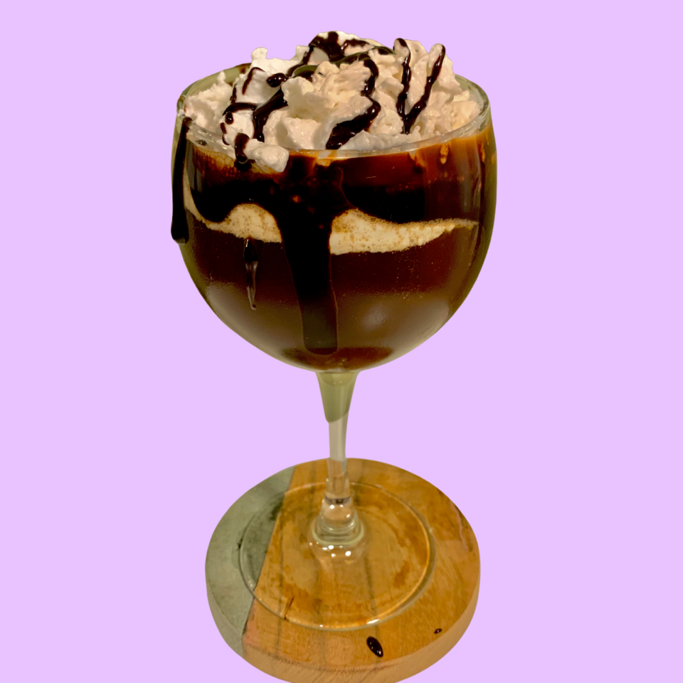 wine glass filled with booze, coffee, and whipped cream with chocolate drizzle