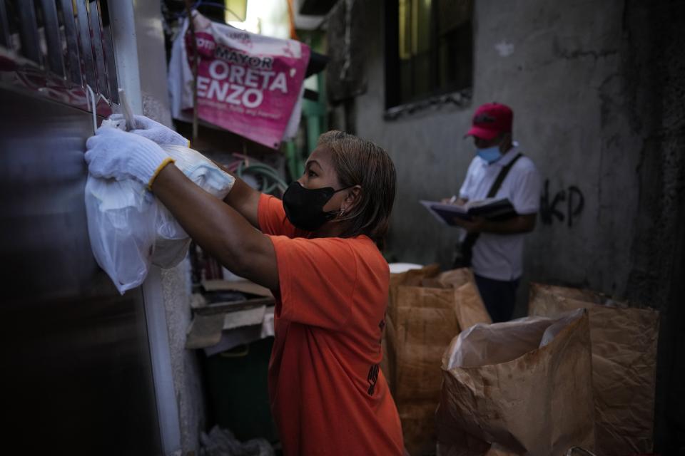 Marilene Capentes collects segregated garbage beside her cart along the streets of Malabon, Philippines on Monday Feb. 13, 2023. Capentes, who is 47, said the trash used to be all mixed together — and heavy — until a local environmental nonprofit started asking residents to separate it a few years ago. (AP Photo/Aaron Favila)