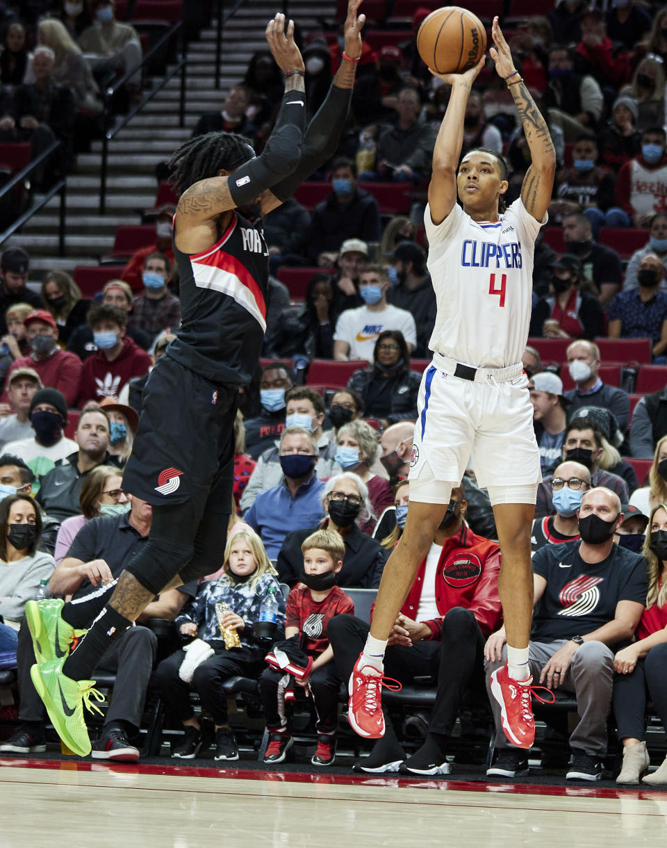 Los Angeles Clippers guard Brandon Boston Jr., right, shoots a three-point basket over Portland Trail Blazers guard Ben McLemore during the first half of an NBA basketball game in Portland, Ore., Monday, Dec. 6, 2021. (AP Photo/Craig Mitchelldyer)