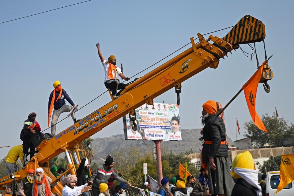 Farmers climb over a crane during a tractor rally as they continue to demonstrate against the central government's recent agricultural reforms in New Delhi on January 26, 2021. (Photo by Money SHARMA / AFP) (Photo by MONEY SHARMA/AFP via Getty Images)