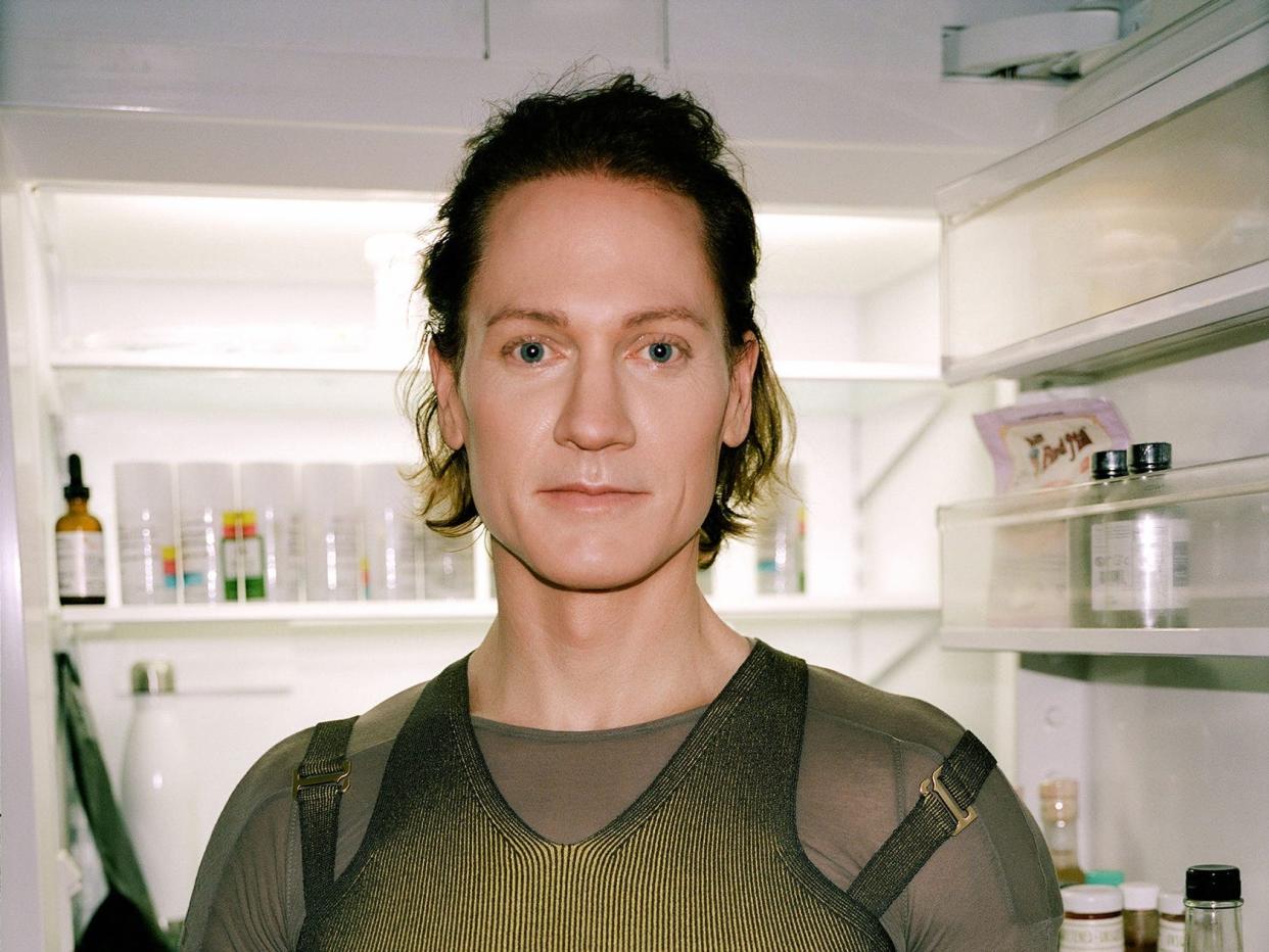 Bryan Johnson standing in a lab room in front of shelves of glass bottles.