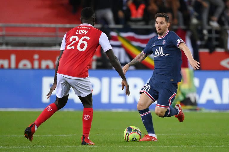 Paris Saint-Germain&#39;s Argentinian forward Lionel Messi (R) runs with the ball towards Reims&#39; Senegalese defender Dion Lopy during the French L1 football match between Stade de Reims and Paris Saint-Germain (PSG) at Stade Auguste Delaune in Reims, northern France on August 29, 2021. (Photo by FRANCK FIFE / AFP)