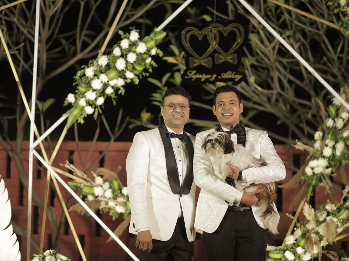 Abhay Dang, left, and Supriyo Chakraborty, holding their dog, are shown at a commitment ceremony they held in 2021 to mark their ninth anniversary, with more than 100 friends and family. (Submitted by Supriyo Chakraborty - image credit)