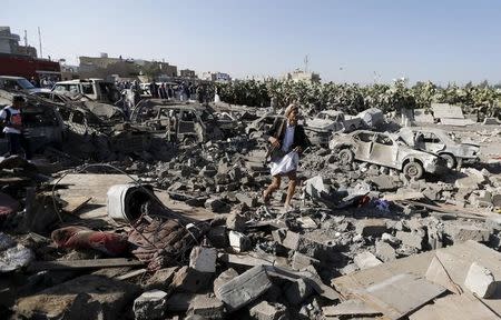 An armed man walks on the rubble of houses destroyed by an air strike near Sanaa Airport March 26, 2015. REUTERS/Khaled Abdullah