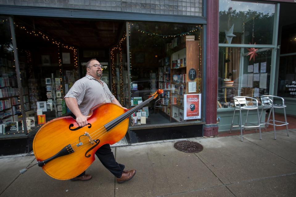 Glen Hurley carries an upright bass along Broadway Street in Frankfort to the Thursday night Bluegrass music jam in Frankfort. May 11, 2017.