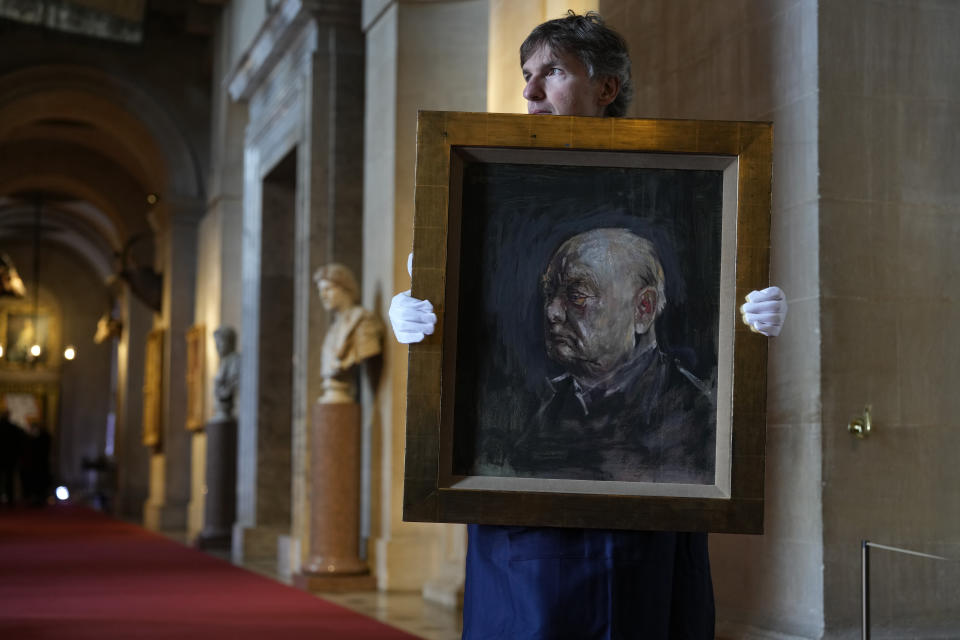 A member of staff from Sotheby's poses for the media with a portrait of the iconic former British Prime Minister Winston Churchill, painted by Graham Sutherland in 1954, at Blenheim Palace, Woodstock, England, Tuesday, April 16, 2024. The portrait will be sold at auction on June 6 with an estimated price of 500-800,000 pounds sterling (US621, 000-1,000,000). Churchill was born at Blenheim Palace on Nov. 30, 1874. (AP Photo/Alastair Grant)