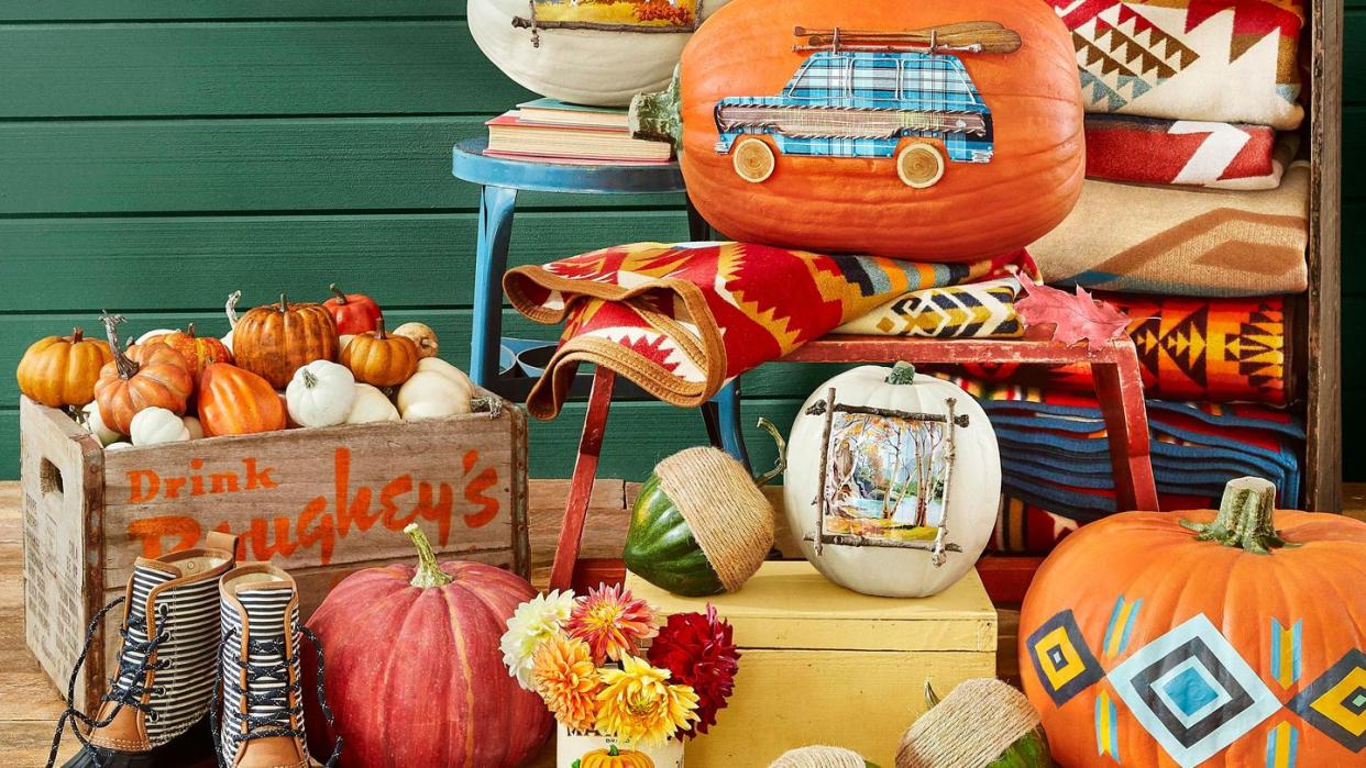 fall pumpkin display styled with mud boots, pendleton blankets, vintage crates and stools, green cabin wall backdrop