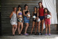 Soccer player Mara Gomez, second from right, poses with her soccer loving family members at their home in La Plata, Argentina, Thursday, Feb. 6, 2020. From left are her mother Carolina Cardozo, sisters Keila, Evelin holding daughter Kima, Kiara and Yamila. Gomez is a transgender woman who is limited to only training with her women's professional soccer team, Villa San Carlos. She is waiting for confirmation from the Argentina Football Association (AFA) she can play. (AP Photo/Natacha Pisarenko)