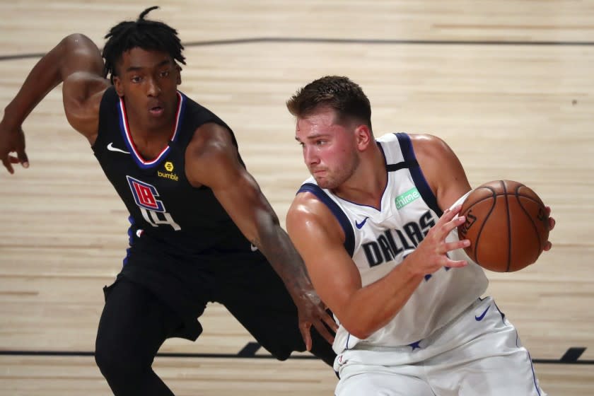 Dallas Mavericks guard Luka Doncic, right, drives to the basket against Los Angeles Clippers guard Terance Mann (14) during the first half of Game 2 of an NBA basketball basketball first-round playoff series, Wednesday, Aug. 19, 2020, in Lake Buena Vista, Fla. (Kim Klement/Pool Photo via AP)