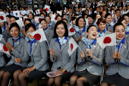 Flight attendants wave Japan's national flags while they wait for the arrival of the Olympic flag during a ceremony to mark the arrival of the flag at Haneda airport in Tokyo, Japan, August 24, 2016. REUTERS/Kim Kyung-Hoon