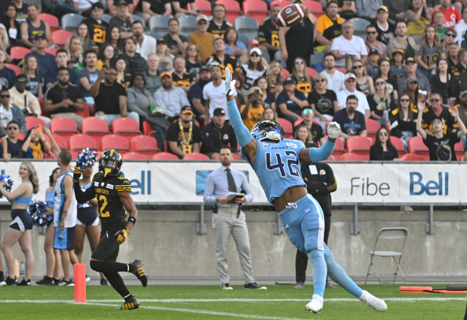 Jun 18, 2023; Toronto, Ontario, CAN; Toronto Argonauts defensive back Qwan’tez Stiggers (42) reaches up to intercept a pass intended for Hamilton Tiger-Cats wide receiver Tim White (12) in the first quarter at BMO Field. Mandatory Credit: Dan Hamilton-USA TODAY Sports