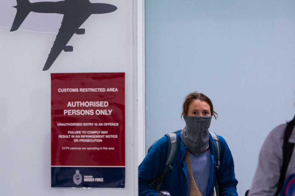 A traveller is seen covering her face at an airport in Melbourne.