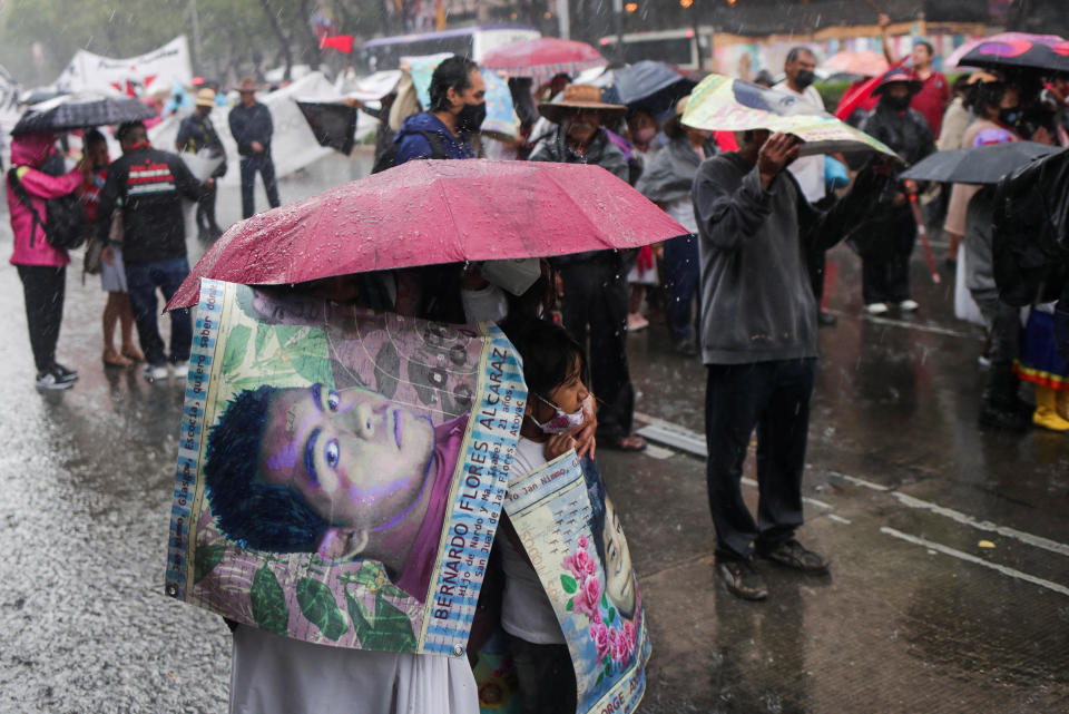 Relatives take cover from the rain with umbrellas and banners with images of the missing students from Ayotzinapa Teacher Training College, as they take part in a march to demand justice for their loved ones, in Mexico City, Mexico, on Aug. 26, 2022. / Credit: HENRY ROMERO / REUTERS