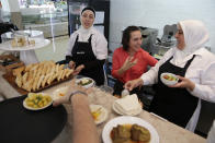 In this picture taken Oct. 2, Serenah Sabat, a 26-year-old Palestinian asylum-seeker from Bethlehem, center, laughs with Fatima Ghannam, right, and Rana, both from Syria, at the Middle Eastern restaurant where they work in Lisbon. Portugal heads to the polls for a general election the coming weekend, with the liberal and migrant-welcoming Socialist Party is tipped for a resounding win, without the loud populists far-right groups that have played hard in some other parts of Europe. (AP Photo/Armando Franca)