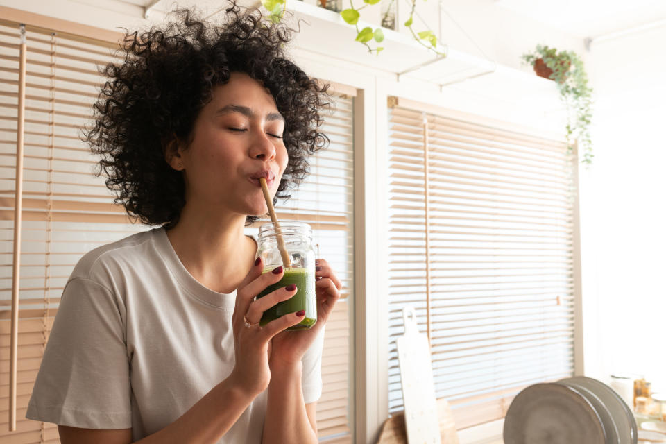 Woman drinking green juice. (Getty Images)