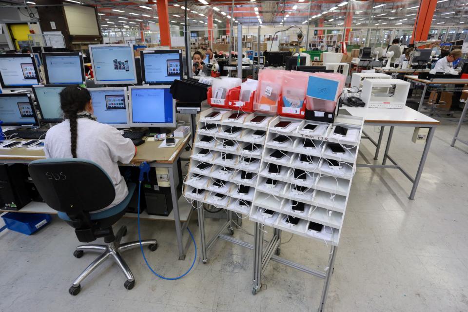 Un empleado de la empresa de reciclaje Love2recycle.fr controla teléfonos inteligentes el 7 de noviembre de 2014 en Brive, en el sur de Francia.  La empresa recoge y repara todo tipo de smartphones antes de lanzarlos al mercado.  AFP PHOTO / NICOLAS TUCAT (Foto de NICOLAS TUCAT / AFP) (Foto de NICOLAS TUCAT/AFP vía Getty Images)