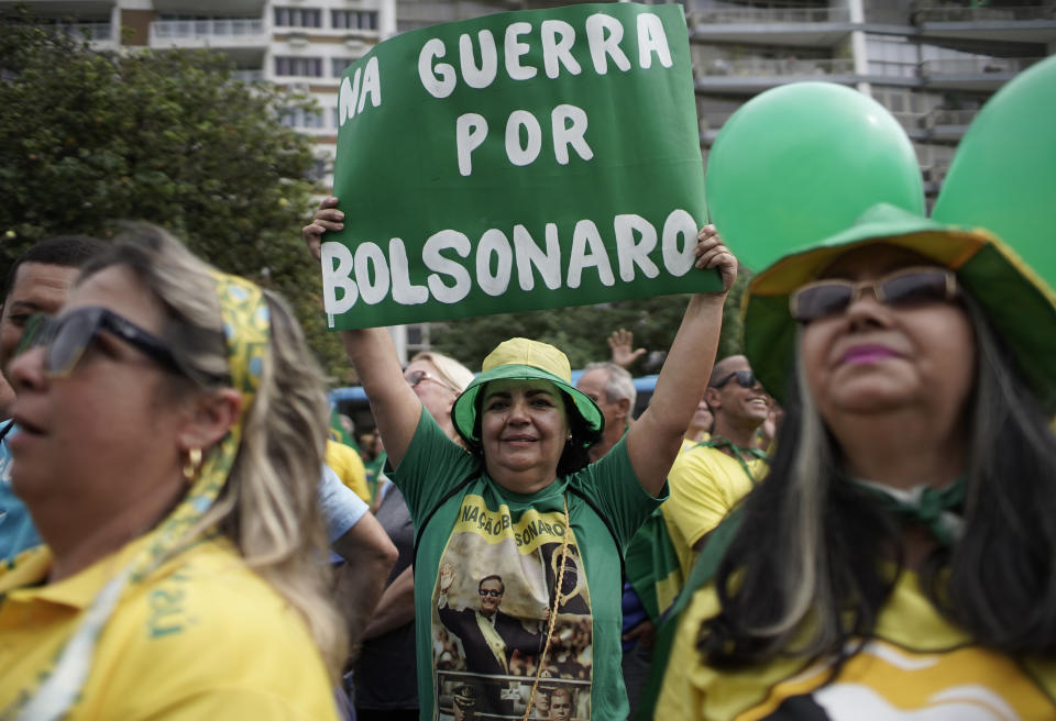 A supporter of Brazil's President Jair Bolsonaro holds a sign that reads in Portuguese: "War for Bolsonaro" during a rally on Copacabana beach in Rio de Janeiro, Brazil, Sunday, May 26, 2019. The pro-Bolsonaro rally follows anti-government protests against education budget cuts as the leader also battles an uncooperative Congress, a family corruption scandal and falling approval ratings after five months in office. (AP Photo/Silvia Izquierdo)