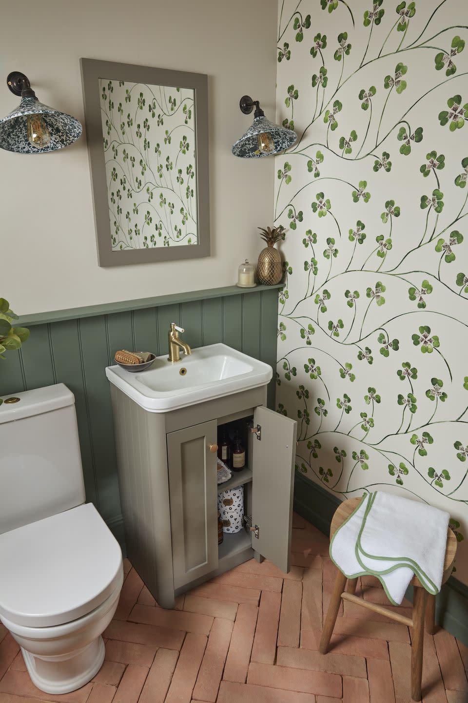 loo with sink and toilet and green wallpaper