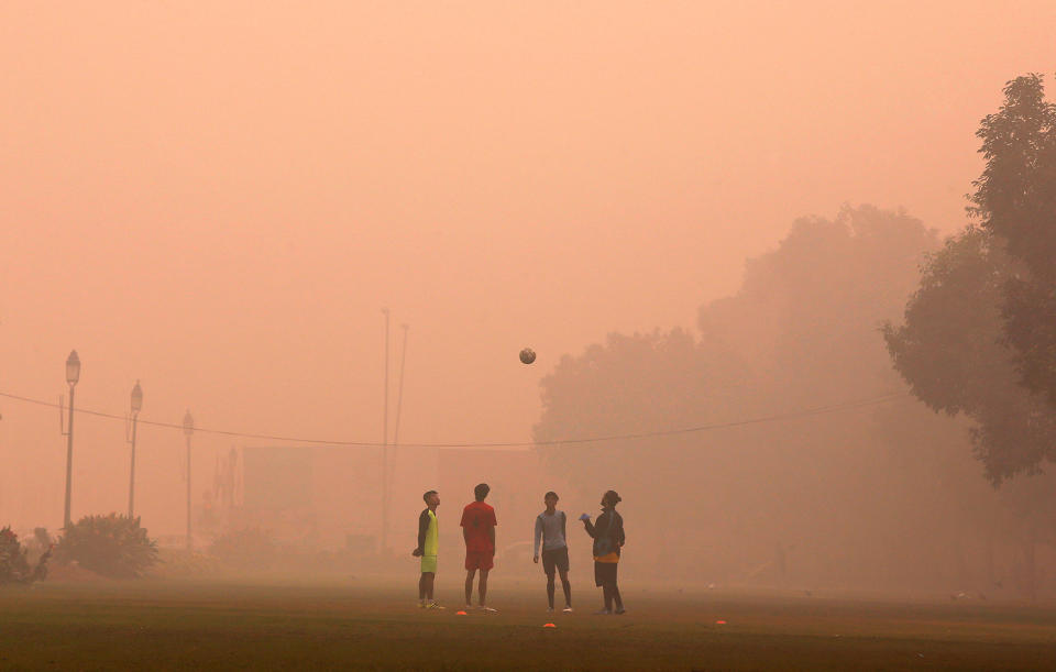 Boys play football in a public park on a smoggy morning in New Delhi