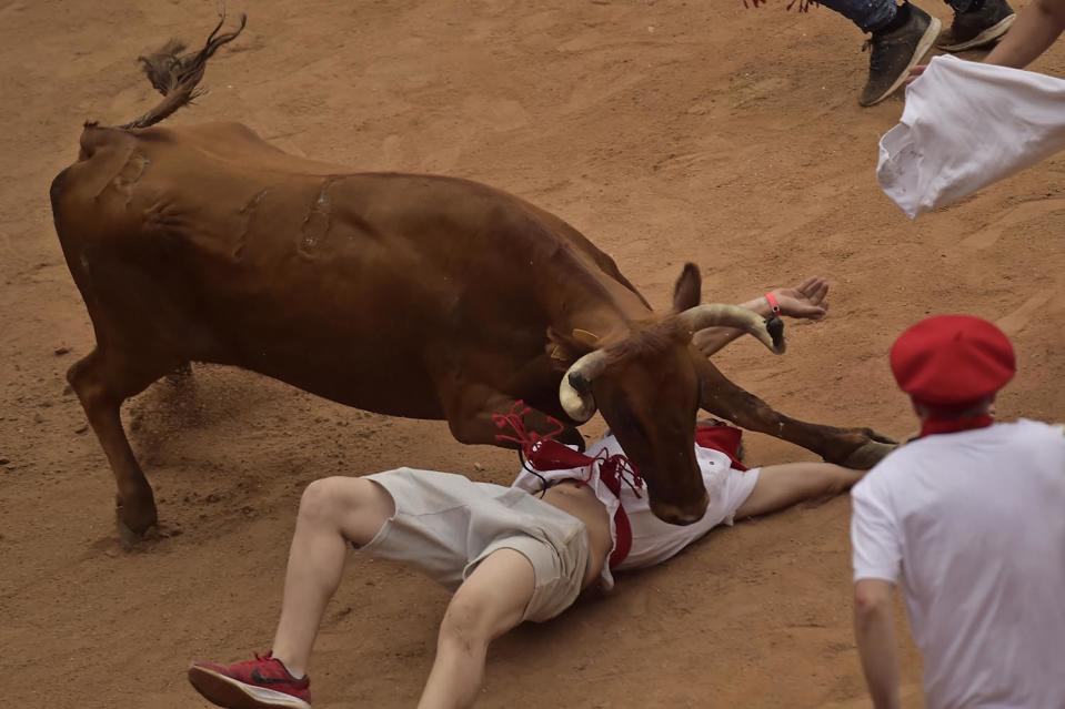 <p>A reveller lies on the ground beneath a calf after the third running of the bulls at the San Fermin Festival, in Pamplona, northern Spain, July 9, 2017. (AP Photo/Alvaro Barrientos) </p>