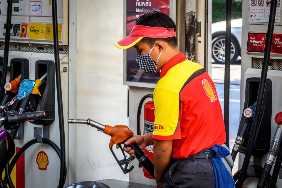 An employee wearing a facemask fills up a car at a gas station in Bangkok on March 9, 2020, as the rapidly spreading coronavirus fans fears over the global economy. (Photo by Mladen ANTONOV / AFP) (Photo by MLADEN ANTONOV/AFP via Getty Images)