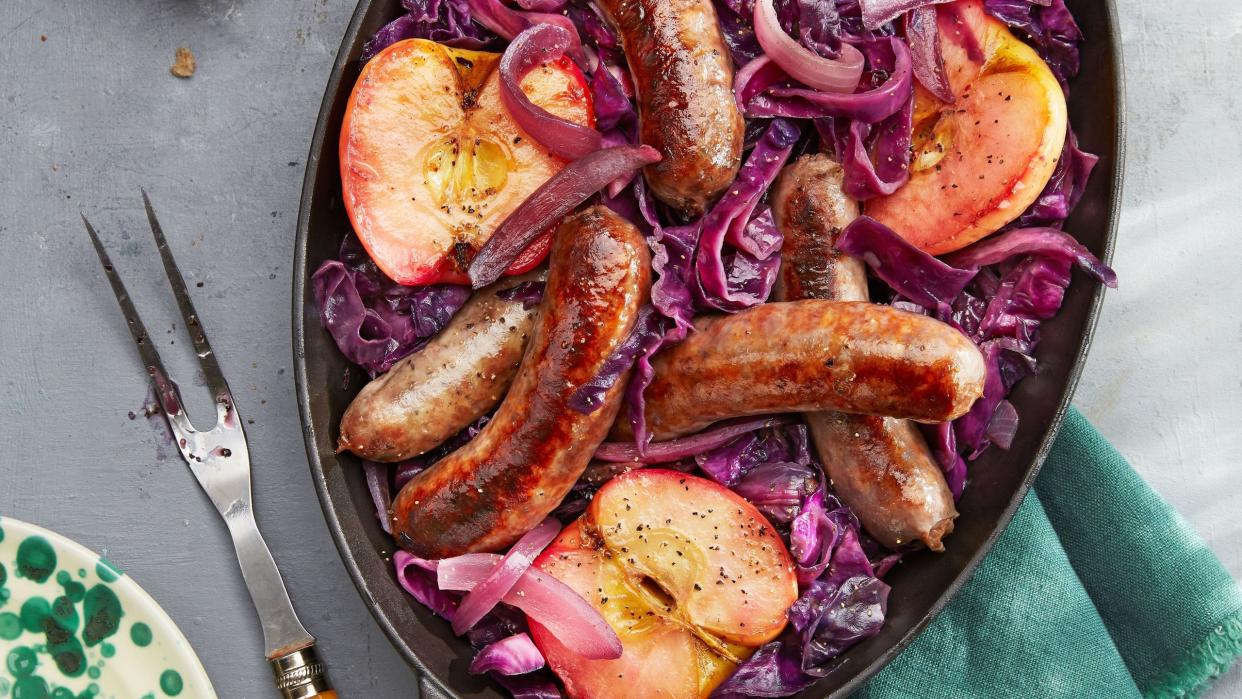 seared sausage with cabbage and pink lady apples in an oval cast iron dish