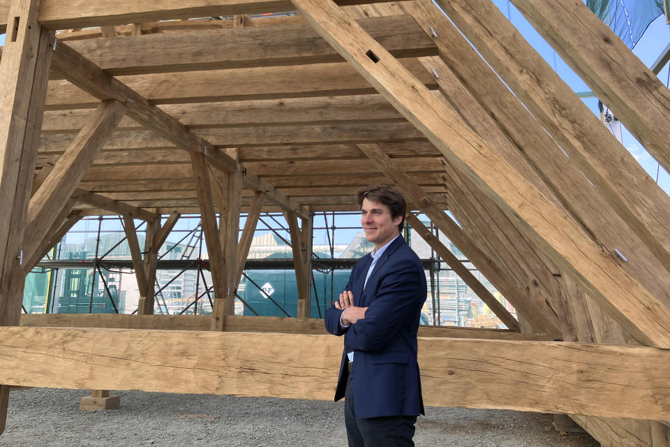 Jean-Baptiste Bonhoure, head of Atelier Perrault, a carpenter and wooden work company, poses next to wooden beams Thursday, May, 25, 2023, near Angers, western France. Carpenters building a new timber frame for the fire-ravaged roof of Paris' Notre Dame Cathedral are using the same tools and techniques as their medieval predecessors. For them, working with hand-axes to fashion oak beams has been like stepping back in time. (AP Photo/Jeffrey Schaeffer)