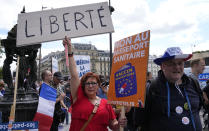 A protestor holds a sign which reads in French, "freedom" and "no to the Covid passport" as she attends a demonstration in Paris, France, Saturday, July 31, 2021. Demonstrators gathered in several cities in France on Saturday to protest against the COVID-19 pass, which grants vaccinated individuals greater ease of access to venues. (AP Photo/Michel Euler)