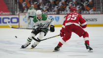 Dallas Stars' Mark Pysyk (13) flips the puck past Detroit Red Wings defenseman Danny DeKeyser (65) in the first period of an NHL hockey game Thursday, April 22, 2021, in Detroit. (AP Photo/Paul Sancya)