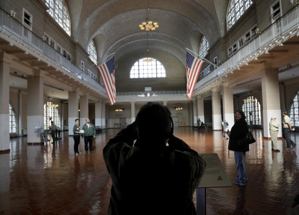 A visitor to the newly re-opened Ellis Island stops to take a picture of the registry room in New York, Monday, Oct. 28, 2013. The island that ushered millions of immigrants into the United States received visitors Monday for the first time since Superstorm Sandy. Sandy swamped boilers and electrical systems and left the 27.5-acre island without power for months. (AP Photo/Seth Wenig)
