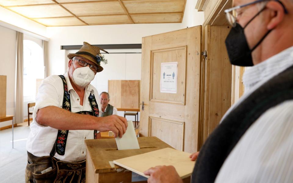 A man wearing traditional Bavarian costume casts his vote during the general elections in Benediktbeuern, Germany, September 26, 2021. REUTERS/Michaela Rehle - MICHAELA REHLE /REUTERS