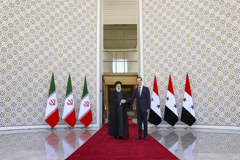 In this photo released by the office of the Iranian Presidency, President Ebrahim Raisi, left, is welcomed by his Syrian counterpart Bashar Bashar in Damascus, Syria, Wednesday, May 3, 2023. (Iranian Presidency Office via AP)